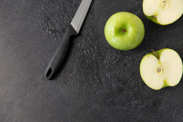 fruits, diet, eco food and objects concept - green apples and kitchen knife on slate stone background