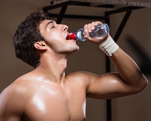 Obraz premium Thirsty man drinking water in sports gym