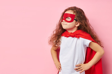 Imagination of superhero. Caucasian child wearing red mask of hero and cloak stand looking side,...