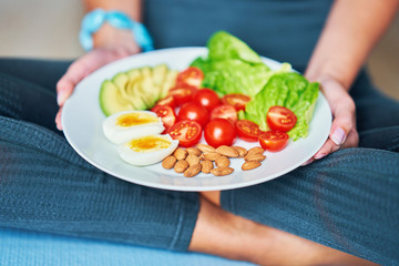 Adult woman eating healthy lunch and sitting on yoga mat