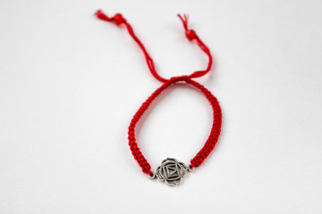 red braded bracelet with chakra (muladhara) on white background