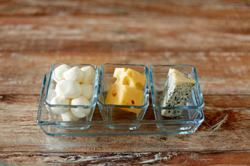 food and eating concept - different kinds of cheese in glass cups