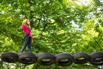Active children. Helmet - safety equipment for Child playing. Cargo net climbing and hanging log. Eco Resort Activities. Safe Climbing extreme sport with helmet. High ropes walk.