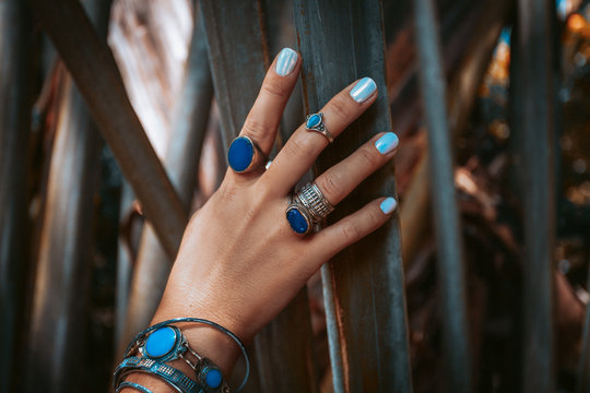close up of woman hand with gemstone rings on tropical background