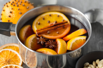 christmas and seasonal drinks concept - pot with hot mulled wine, orange slices and aromatic spices...