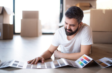 Mature man with boxes moving in new house, looking at color swatch.