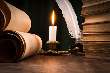 Scrolls of parchment, a stack of books, and a lit candle