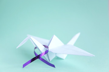  White paper crane with purple ribbon on mint paper background. Alzheimer's disease, Pancreatic...