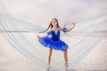 girl ballerina dancer in a  blue  dress on a snow-white salty dried lake. Fantastic landscape and a girl in  punata and a  blue dress.
