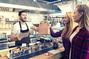 Waiter serving takeaway food to customers at counter in small family eatery restaurant  - 301955215