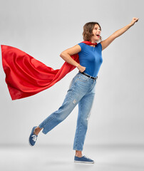 women's power and people concept - happy woman in red superhero cape making flying pose over grey background © Syda Productions