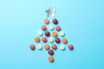 Christmas tree made of candies on blue background, space for text