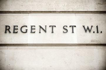 Simple sign for Regent Street in traditional raised metal lettering on old weathered wall in London, UK