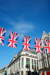 Fototapeta na wymiar Union Jack flag decorations strung above the streets of London, UK against bright blue sky