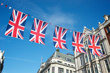 Union Jack flag decorations strung above the streets of London, UK against bright blue sky
