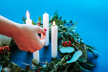 Woman lighting the candles of a Christmas Wreath 