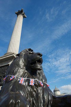 View of Trafalgar Square lion, installed in 1867, with British Union Jack flag bunting  at the foot of the Nelson's Column in London, UK