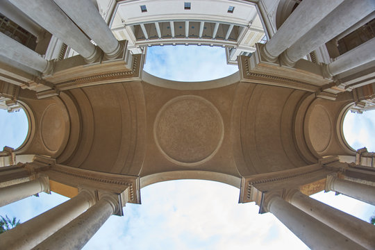 Upward wide view of arch and roman style building in background