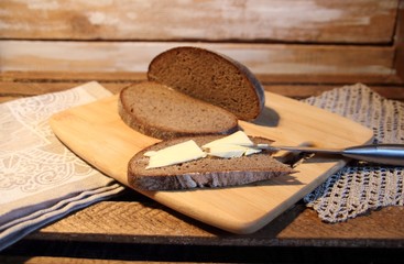 Brown bread with butter on wooden board with knife, milk glass in rustic style