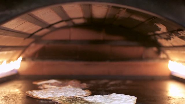 Making Manakeesh inside a gas heated oven, slow motion. Manakeesh is a type of pastry, which is a popular Lebanese and Levantine food consisting of dough topped with thyme, cheese or meat