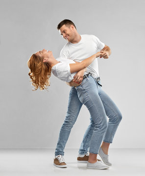 relationships and people concept - portrait of happy couple in white t-shirts dancing over grey background