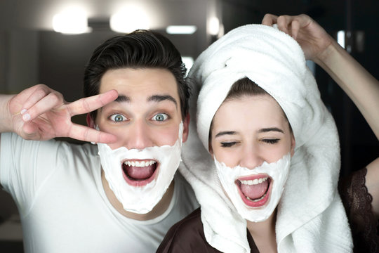 young funny couple handsome man and beautiful woman in turban having fun both with shaving foam on their faces in bathroom in morning playful mood