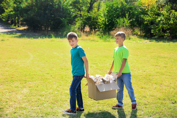 Boys gathering garbage outdoors. Concept of recycling