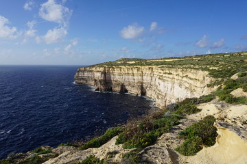 Fototapeta na wymiar Gozo cliffs, beautiful, stunning view from the walking path around Gozo; after dry summer the island starts to be green during the autumn
