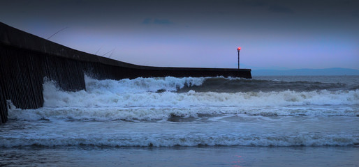 High tide fishing rods and breaking waves at blue hour on the West Pier on Swansea Bay, South...