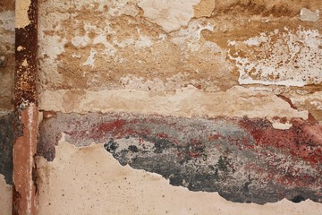 Colorful plaster and paint peeling from a wall in multiple layers