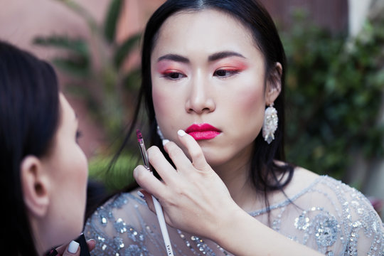 Make up artist doing creative makeup for Chinese fashion model outdoors