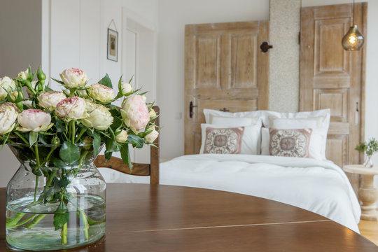 Fresh roses flowers on wooden table in modern bedroom