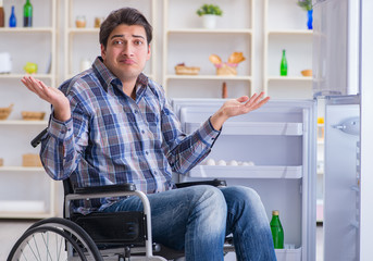 Young disabled injured man opening the fridge door