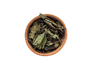 Dry leaves of Melissa officinalis in a wooden Cup on a white background.