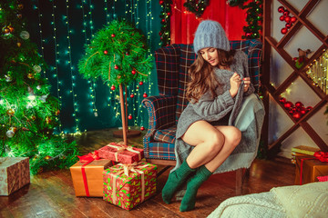 Obraz na płótnie Canvas Christmas portrait of a beautiful girl. A young girl with a Christmas tree and gifts.