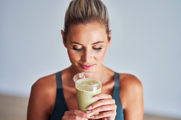 Adult woman drinking healthy smoothie after workout