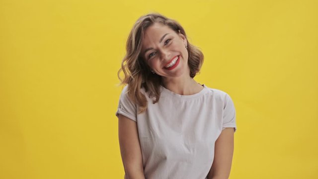 Surprising and happy young woman with red lips laughing while looking at the camera over yellow background isolated                                                                          