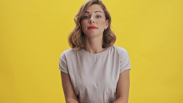 Nice young woman with red lips listen and agree with something while looking at the camera over yellow background isolated                                                                          
