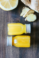 Healthy Ginger lemon shots in small glass bottles on wooden background