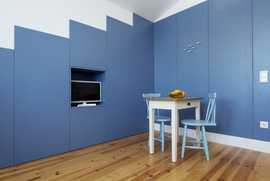 Minimal interior design kitchen in small apartment. Blue walls, yellow lemons on little table, tv