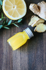 Healthy Ginger lemon shots in small glass bottles on wooden background