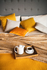 Wood tray with tea on orange bed.