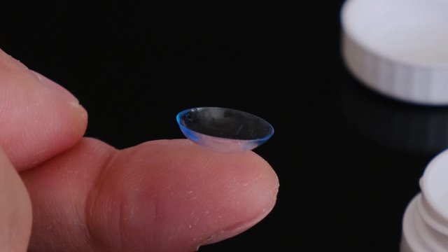 Toric contact lens on a fingertip - extreme closeup details.