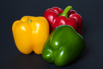 Fresh vegetables Three sweet Peppers on darck background.