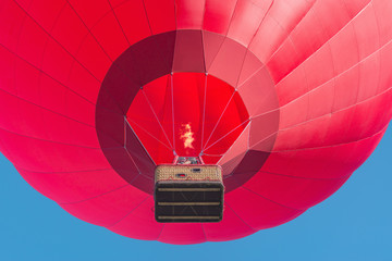 Red hot air balloon on blue sky background.