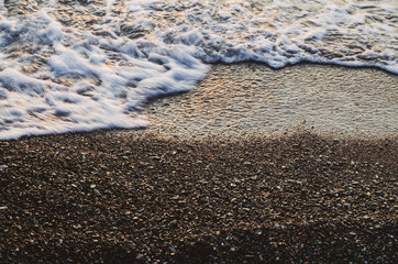 A bubbling wave in motion on wet small pebbles