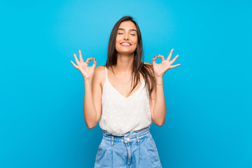 Young woman over isolated blue background in zen pose - obrazy, fototapety, plakaty
