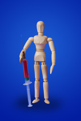 Obraz na płótnie Canvas Wooden toy figure with syringe on blue