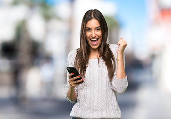 Young hispanic brunette woman surprised and sending a message at outdoors