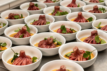 Many beetroot khinkali on mashed potatoes in plates in a restaurant kitchen.